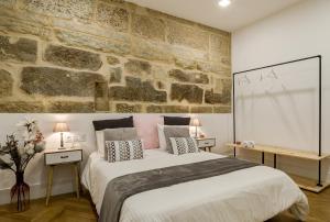 Un dormitorio con una cama grande y una pared de piedra. en Verdura Suites ArchSense Apartments, en Pontevedra