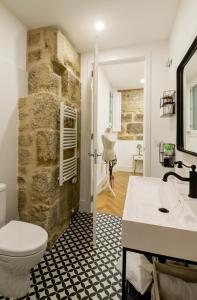 a bathroom with a stone wall and a toilet and a sink at Verdura Suites ArchSense Apartments in Pontevedra