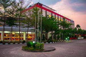 a large building with a lot of windows and trees at Kyriad Arra Hotel Cepu in Cepu