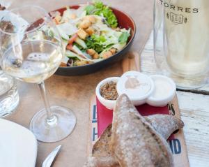 einen Tisch mit einem Teller Essen und einem Glas Wein in der Unterkunft Hotel Victoria in Bergen aan Zee