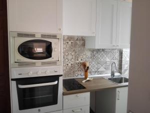 a white kitchen with a microwave and a sink at El Trasgu in Lastres