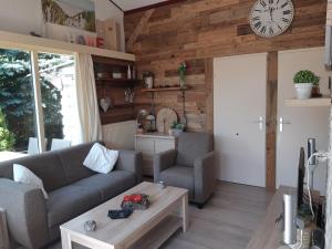 a living room with a couch and a clock on the wall at Zonnig Zuid in Dirkshorn