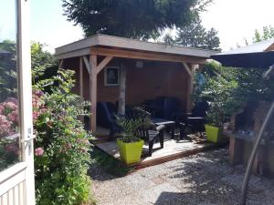 a wooden pergola with a table and chairs in a garden at Zonnig Zuid in Dirkshorn