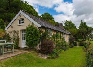 a small house with a garden and a bench in the yard at Dolgenau Cottages in Trefeglwys