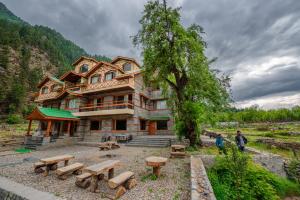 a large building with picnic tables in front of it at Hotel Batseri SANGLA in Sāngla
