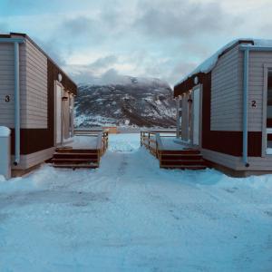 dos casas en la nieve con una montaña en el fondo en Mjøsvang Kafe, en Vang I Valdres