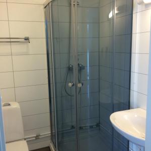 a shower with a glass door next to a sink at Mjøsvang Kafe in Vang I Valdres