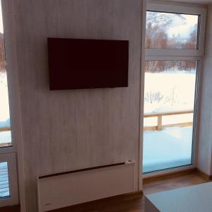 a flat screen tv on a wall next to two windows at Mjøsvang Kafe in Vang I Valdres