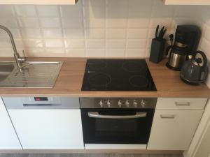 a kitchen with a stove and a sink at Ferienwohnung an der Wieke in Wiesmoor