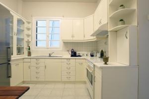 cocina blanca con armarios blancos y ventana en Acheiropoietos Apartment, en Tesalónica