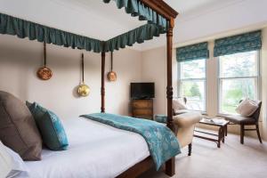 a bedroom with a four poster bed and a chair at Penmorvah Manor Hotel in Falmouth