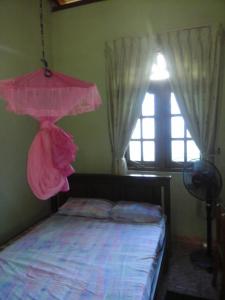 1 dormitorio con cama rosa y ventana en Colombo 20 minutes by train en Wattala