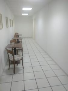 Habitación con mesas, sillas y suelo de baldosa blanca. en hotelverbania, en Sabaudia