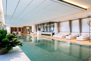a pool in a hotel with white couches and a lobby at Rosewood Phnom Penh in Phnom Penh