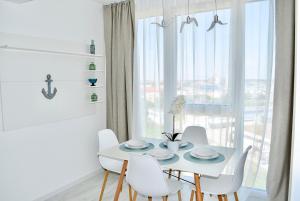 un comedor blanco con mesa, sillas y ventana en Mediterranean Style Apartment, en Timisoara