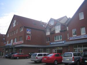 duży ceglany budynek z samochodami zaparkowanymi na parkingu w obiekcie Neustädter Hof Hotel Garni w mieście Neustadt am Rübenberge