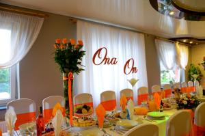 a table with white chairs and a one oh sign on the wall at Noclegi i Restauracja Gracja in Bełchatów