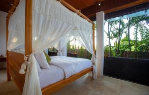 a bedroom with a canopy bed and a large window at Anginsepoi in Canggu