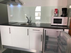a kitchen with white cabinets and a sink and a microwave at Céntrico Apto 6 pax, TABLERO 2 , cerca de Playa Inglés in El Tablero