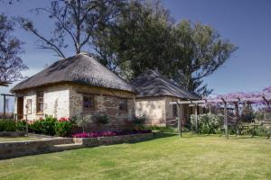 a small stone house with a thatched roof at Dalmore Guest Farm in Bergville