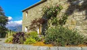 a stone building with flowers on the side of it at Maison d'Hôtes Zella in Bains de Guitera