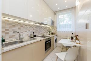 a white kitchen with a sink and a dishwasher at CityPark Villa Flat in Budapest