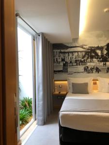 ein Hotelzimmer mit einem Bett und einem großen Fenster in der Unterkunft NDS Prestige Guest House and Suites - by Rocha Prestige in Portimão