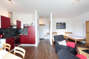 a kitchen and a living room with red cabinets at Yachthafendomizil 2 in Greifswald