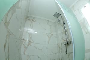 a shower in a bathroom with a white marble wall at Apartment on Registon Kochasi in Samarkand