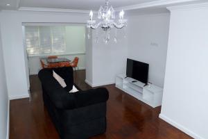 sala de estar con sofá negro y TV en Apartment on Registon Kochasi, en Samarkand
