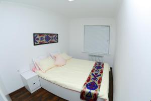 a small bedroom with a bed with white sheets and pink pillows at Apartment on Registon Kochasi in Samarkand