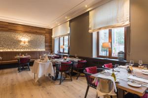a dining room with tables and chairs and windows at Hotel Bayerischer Hof in Erlangen