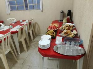 una mesa roja con platos y tazones de comida. en Hotel Santa Marta, en Ribeirão Preto