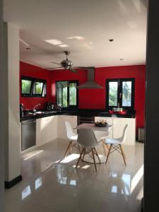 eine Küche mit roten Wänden sowie einem Tisch und Stühlen in der Unterkunft Wild Palms in Ban Tai
