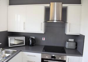 a kitchen with white cabinets and a stove top oven at Kelpies Serviced Apartments Alexander- 2 Bedrooms in Falkirk