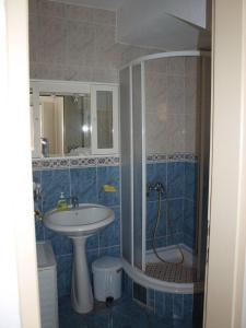 een blauwe betegelde badkamer met een wastafel en een douche bij Casa M & S in Petrovac na Moru