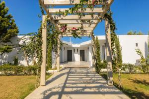 a pathway leading to a white house with a pergola at Venus Resort in Tsilivi