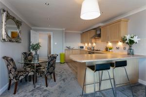 a kitchen with a counter and a table and chairs at Harris Retreat - Donnini Apartments in Ayr +13 photos
