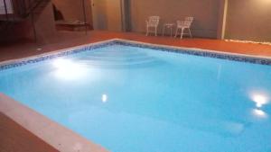 a large blue swimming pool with chairs and a table at Apart Hotel Turey in Santo Domingo