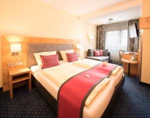 a hotel room with a large bed with a red blanket at AKZENT Hotel Krone in Helmstadt