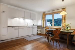 a kitchen with white cabinets and a table and chairs at Hof Kurzamann in Klösterle