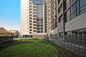 a large building with a grassy yard in front of a building at SANDTON APARTMENT MASINGITA TOWERS 15 WEST Rd SOUTH in Johannesburg