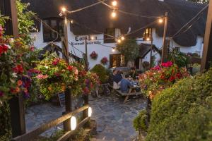 a group of people sitting outside of a building with flowers at The Cott Inn in Totnes