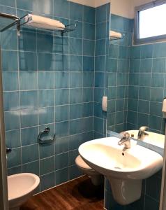 uma casa de banho em azulejos azuis com um lavatório e um WC em Hotel Principe di Piemonte em Rimini
