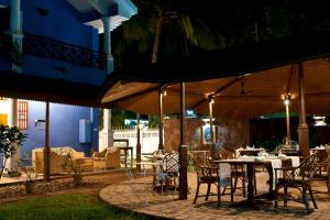 a patio with tables and chairs under an umbrella at Presa di Goa - Managed by Smith and Appy in Calangute
