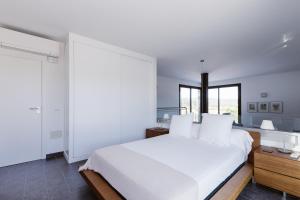 ein weißes Schlafzimmer mit einem großen Bett und einem Fenster in der Unterkunft Can Guasch in Sant Llorenç de Balàfia