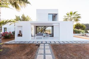 a white house with palm trees and a patio at Can Guasch in Sant Llorenç de Balafia