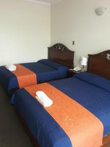 a room with three beds with blue and orange at Hostal Tukos La Casa Real in Potosí