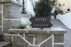 a sign for a guest house on a stone wall at 4U Lisbon Airport Suites in Lisbon