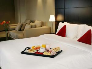 uma bandeja de comida numa cama num quarto de hotel em HTL City Baires em Buenos Aires
